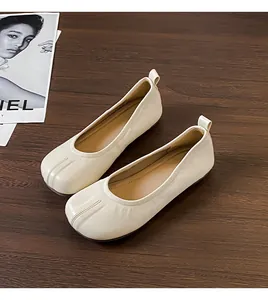 Dettaglio di ballerine vintage beige con pieghe e design a punta divisa su legno scuro.