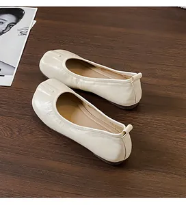 Primo piano di ballerine retrò a pieghe stile tabi in pelle color crema.