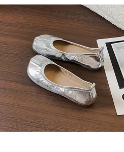 Dettaglio ballerine argentate metallizzate con finto design Tabi a punta divisa su legno.