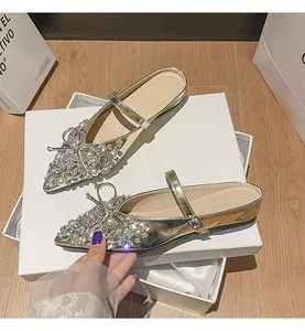 Detailansicht goldener Pantoletten mit Strasssteinen und Perlenbogen auf Geschenkboxen