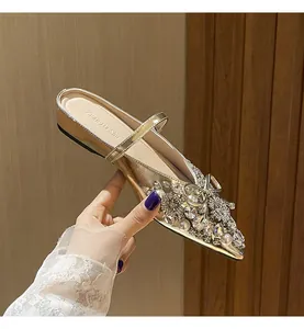 Nahaufnahme goldener flacher Pantoletten mit Strass- und Perlenverzierung