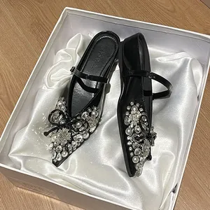 Elegante schwarze flache Maultiere mit spitzen Zehen und glitzernden Strass-Perlen-Schleifen.