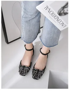 Close-up of black rhinestone flat shoes with bow and ankle strap on model's feet