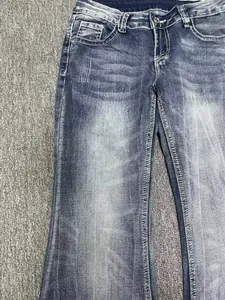 Close-up of vintage blue washed denim fabric and stitching on low waist flare jeans.