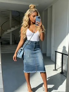 Close-up of high-waisted distressed denim midi skirt with raw hem detailing.