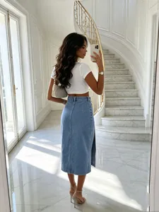 Stylish high-waisted denim midi skirt with side slit and washed finish shown in interior