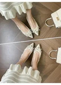 Dettaglio delle scarpe basse crema a punta con fiocco di strass scintillanti