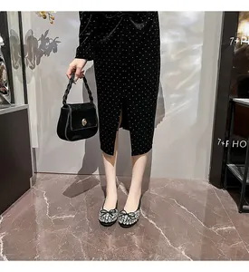 Detailansicht schwarzer flacher Schuhe mit funkelnder Strass-Schleife auf dem flachen Mund