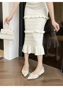 Dettaglio delle ballerine a punta bianche con strass scintillanti e fiocchi eleganti.