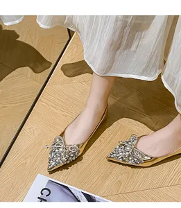 Dettaglio di scarpe da sposa dorate a punta piatta con fiocco di strass di lusso