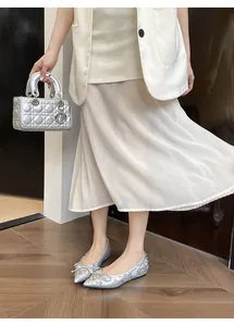 Dettaglio di scarpe basse argento con fiocco di strass e design a punta sottile