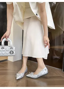 Scarpe basse argentate a punta con fiocco di strass indossate da una modella