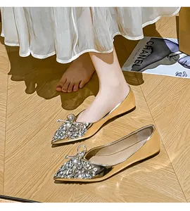 Dettaglio di ballerine a punta oro champagne con elegante fiocco di strass su modella