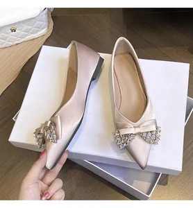Dettaglio di ballerine a punta in raso champagne con fiocchi di strass brillanti.
