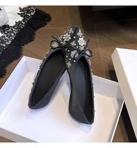 Dettaglio di ballerine nere a punta con strass scintillanti e un grazioso fiocchetto.