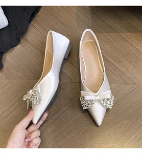 Vista ravvicinata di eleganti ballerine da sposa avorio a punta con fiocco di cristalli