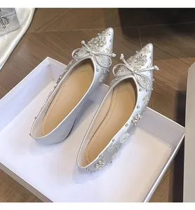 Dettaglio di eleganti ballerine argento a punta con fiori di strass e fiocchetto