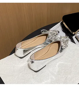Dettaglio di scarpe basse da sposa argento con fiocco in strass e perle di lusso.