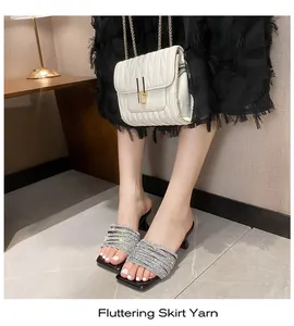 Detail view of silver rhinestone high-heeled sandals styled with a black skirt