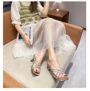 Elegant French style gold rhinestone high heel sandals worn by a model in a chic room.