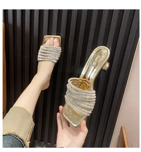 Close-up of sparkling rhinestone straps on golden French-style mule sandals
