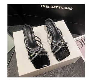 Detailed view of elegant black heeled sandals featuring shimmering rhinestone crisscross straps