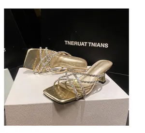 Detail view of gold high-heeled sandals with shimmering rhinestone crisscross straps.