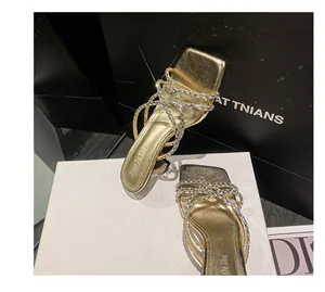 Detail of gold high-heeled sandals featuring sparkling rhinestone-encrusted crisscross straps.