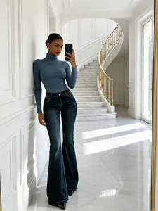 Eleganti jeans a zampa blu scuro abbinati a un dolcevita grigio in interni di lusso.