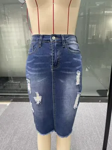 Close-up of a high-waisted denim midi skirt featuring distressed rips and a frayed hem.