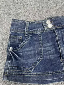 Detail of high-waisted distressed denim skort with double button closure