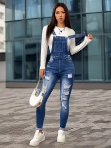 Full body view of women's skinny distressed denim overalls in an urban setting