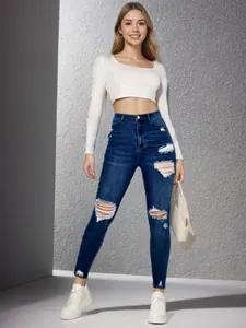 Jean skinny déchiré à taille haute pour femme, présenté dans un décor de studio