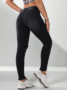 Achteraanzicht van zwarte skinny jeans voor dames met stretch en gescheurde knieën
