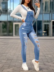 Full view of women's distressed denim bib overalls featuring a slim fit silhouette
