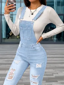 Close-up of slim-fit ripped denim overalls with stretch fabric and suspender detail.