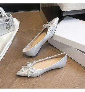 Eleganti ballerine a punta argento con fiocco di strass su un pavimento in legno chic.