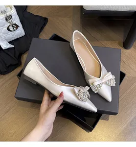 Dettaglio di eleganti ballerine bianche a punta con fiocco in strass scintillanti.