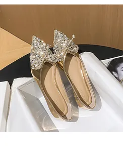 Dettaglio di scarpe basse dorate con fiocco lussuoso in strass e perle brillanti.