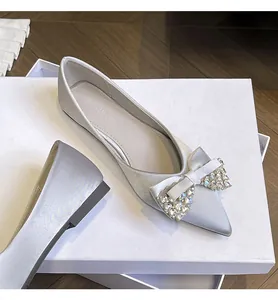 Dettaglio di scarpe basse a punta in raso argento con fiocco di strass