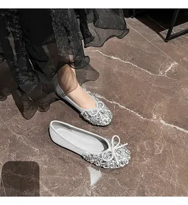 Detailansicht glänzender silberner flacher Schuhe mit Strassschleife auf Marmorboden