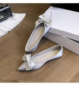 Vista dettagliata di eleganti ballerine argento a punta con fiocco di lusso e strass