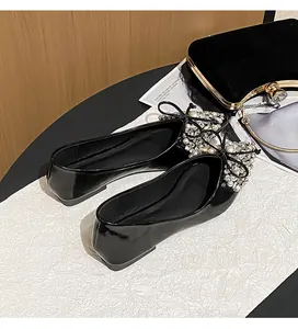 Primo piano di eleganti ballerine in vernice nera con fiocco in perle e cristalli.