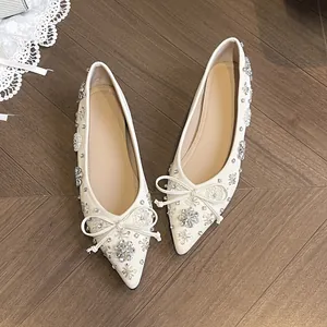 Eleganti ballerine bianche a punta con dettagli floreali in strass e fiocco delicato.