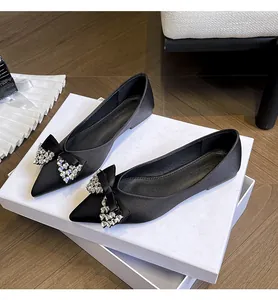 Vista dettagliata di eleganti ballerine in raso nero con fiocchi in strass lucidi.