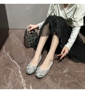 Elegante silberne flache Schuhe mit funkelnder Strass-Schleife auf Marmorboden