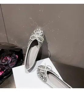 Detailansicht eleganter silberner Ballerinas mit funkelnden Strasssteinen und Schleife