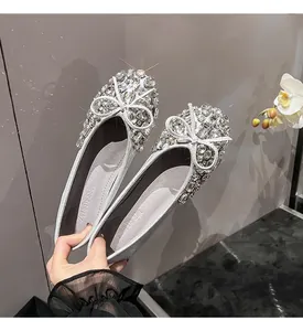 Nahaufnahme silberner Ballerinas mit funkelnder Strass-Schleife und Glitzereffekt.