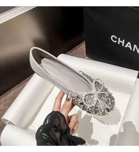 Detaillierte Makroansicht eleganter silberner flacher Schuhe mit funkelnder Strass-Schleife