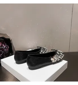 Elegante schwarze Ballerinas mit funkelnden Strasssteinen und Schleifendetails auf Weiß.